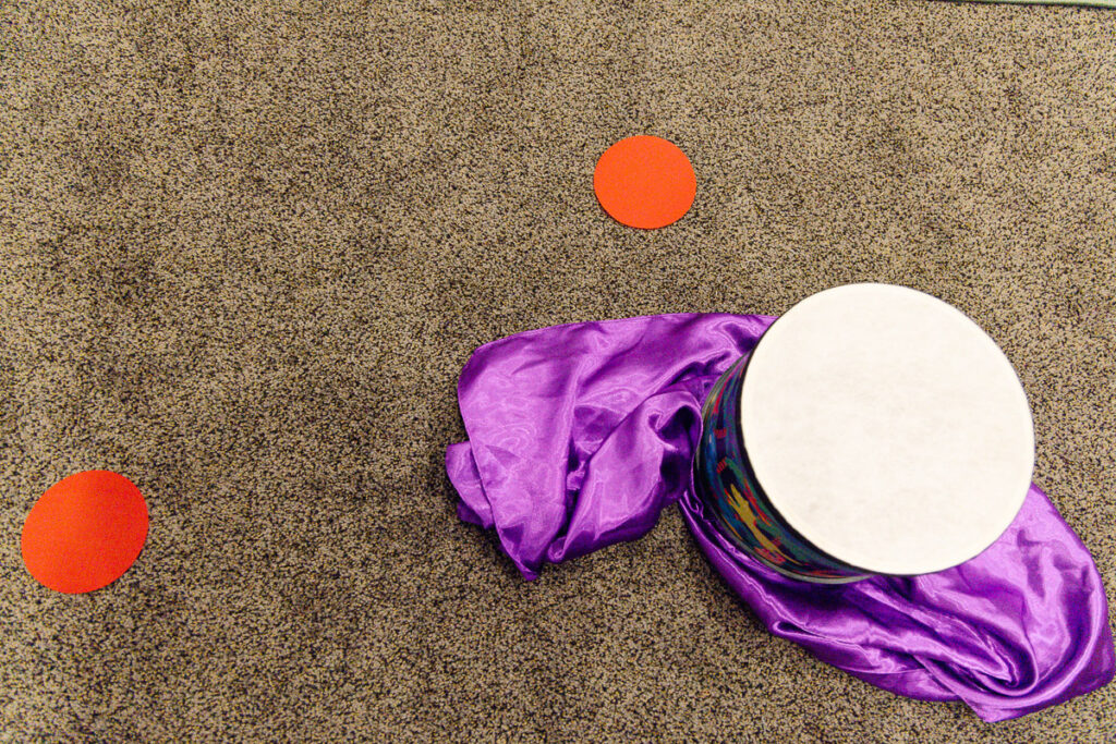 Red circle floor markers and a drum set on a scarf that can be used to sing with children and create order